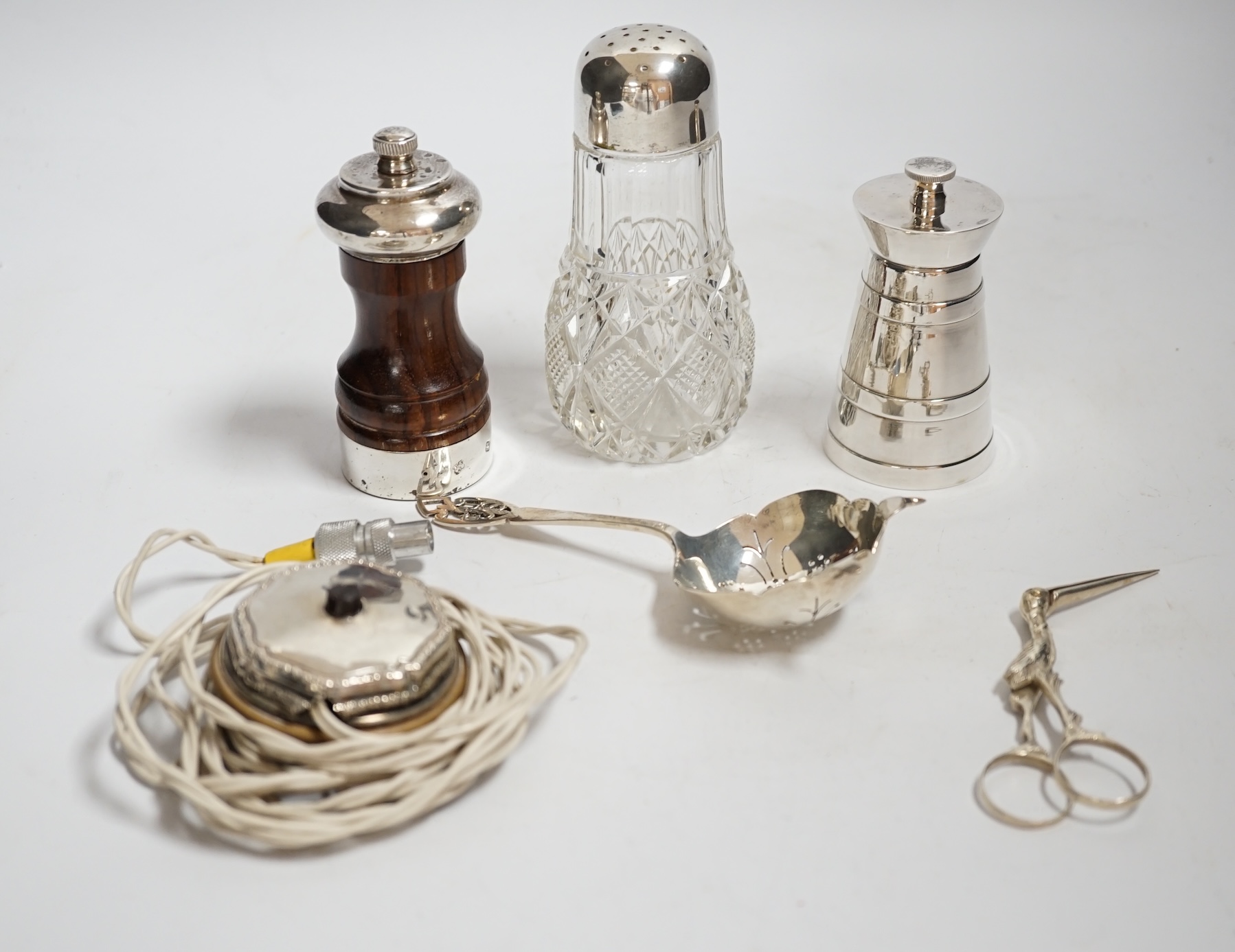 Two modern silver mounted pepper mills, largest 10.2cm, a silver tea strainer, 800 standard white metal mounted glass caster and sundry other items.